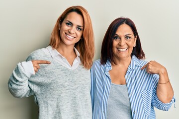Latin mother and daughter wearing casual clothes pointing finger to one self smiling happy and proud
