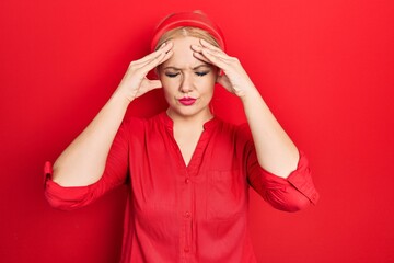 Young blonde woman wearing casual red shirt suffering from headache desperate and stressed because pain and migraine. hands on head.