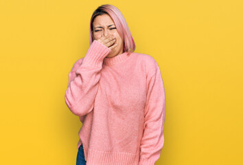 Hispanic woman with pink hair wearing casual winter sweater smelling something stinky and disgusting, intolerable smell, holding breath with fingers on nose. bad smell
