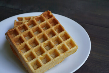 Warm waffles in a white plate on a black wooden table                 