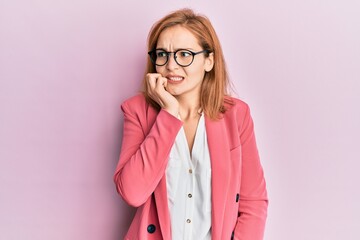 Young caucasian woman wearing business style and glasses looking stressed and nervous with hands on mouth biting nails. anxiety problem.