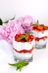 Natural dessert with fresh strawberry, yogurt, chia seeds and fresh mint on the table. Healthy breakfast. Сlose-up.