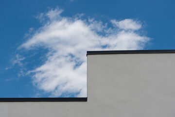 nondescript stucco walled building against blue sky with clouds