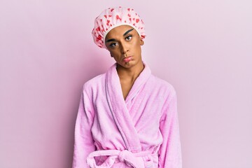 Hispanic man wearing make up wearing shower towel cap and bathrobe depressed and worry for distress, crying angry and afraid. sad expression.