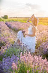 Fototapeta na wymiar girl in a hat on a lavender field at sunrise. Harmony with nature.