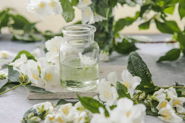 Fototapeta na wymiar Jasmine essential oil and fresh jasmine blossom. Alternative medicine and natural body care cosmetics. Fresh buds of white flowers.