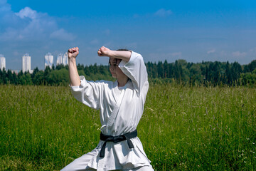 teen girl training karate kata outdoors, performs the haiwan uke movement