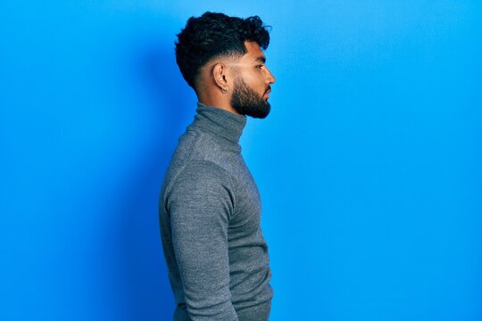 Arab Man With Beard Wearing Turtleneck Sweater Looking To Side, Relax Profile Pose With Natural Face And Confident Smile.