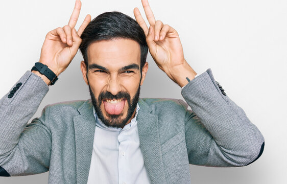 Young hispanic man wearing business clothes posing funny and crazy with fingers on head as bunny ears, smiling cheerful