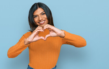 Young latin transsexual transgender woman wearing casual clothes smiling in love doing heart symbol shape with hands. romantic concept. - obrazy, fototapety, plakaty
