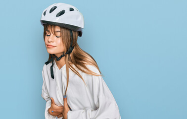Teenager caucasian girl wearing bike helmet with hand on stomach because indigestion, painful illness feeling unwell. ache concept.