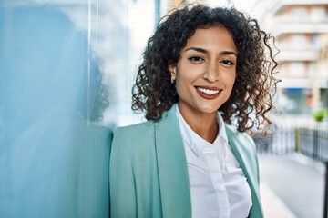 Young hispanic business woman wearing professional look smiling confident at the city leaning on the wall - obrazy, fototapety, plakaty