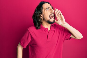 Young hispanic man wearing casual clothes shouting and screaming loud to side with hand on mouth. communication concept.
