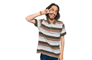 Young hispanic man wearing casual clothes doing peace symbol with fingers over face, smiling cheerful showing victory