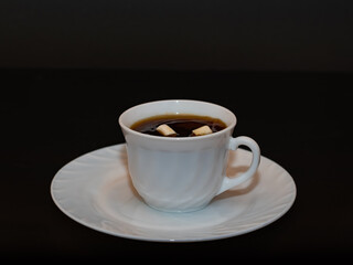 white cup of fcoe with marshmallow black background