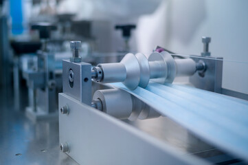 Close up of machine producing surgical mask in modern factory, Covid-19 protection and medical concept.