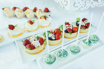 Candy bar. White festive table with deserts, strawberry tartlet and cupcakes. Wedding. Reception Tartlets