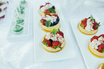 Candy bar. White festive table with deserts, strawberry tartlet and cupcakes. Wedding. Reception Tartlets
