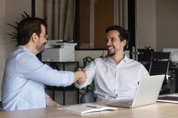 Obraz premium Smiling hr manager shaking successful candidate hand, greeting at job interview or congratulating with hiring, advisor businessman making great deal with customer or business partner at meeting