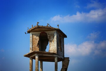 broken watch tower in isloated place on a hill to with blue sky at background