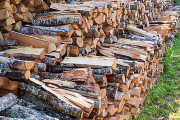 Stocks of firewood for the winter from several woodpiles of different levels. There are birch and alder logs. Background. Texture.