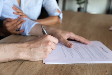 Close up cropped of young couple signing contract at meeting, family closing successful insurance...