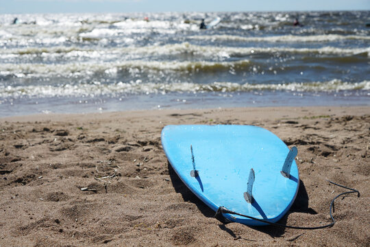 A Surfboard Lying On The Sand Close Up. Blue Surf Board Lies On The Sandy Beach