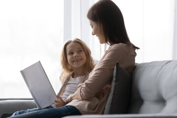 Curious little girl of elementary school age enjoy educational activity with caring mother tutor...