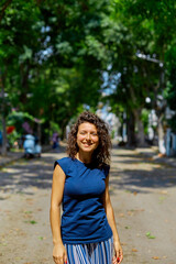 Beautiful curly brunette girl model walks on a summer day