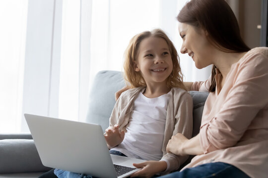 Young Nanny Preteen Girl Ward Sit On Couch Talk Watch Education Video Channel On Laptop Surf Social Networks. Happy Family Of Single Mom And Child Daughter Use Computer Discuss Online News. Copy Space