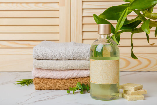 Natural Soap, towels and bath oil, bodycare products on background of bathroom wooden louvered doors. Home spa. Everyday hygiene. Eco-friendly hair care products. Natural cosmetics. Shower gel