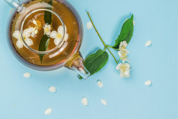 Jasmine flowers brewed in a teapot on a blue background.