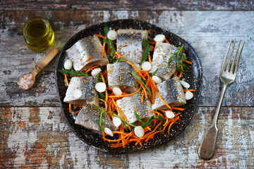 Herring fillet pieces marinated with spices on a plate.