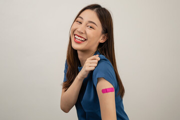 Happy Asian woman showing his arm and bandage after they get a vaccine.