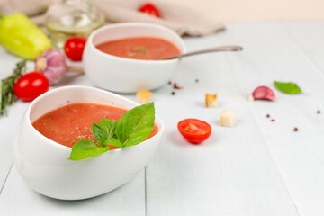 Cold refreshing gazpacho soup made of tomatoes, sweet peppers and cucumbers. two white bowls with tomato soup puree
