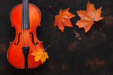 Old violin with yellow autumn maple leave. Top view, close-up on dark vintage background