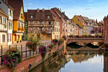 Fototapeta na wymiar Colmar, France, late day view with half timbered houses, flowers, bridge and reflections in the beautiful canals