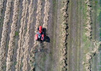 Obraz premium Aerial image of tractor with hay tedders