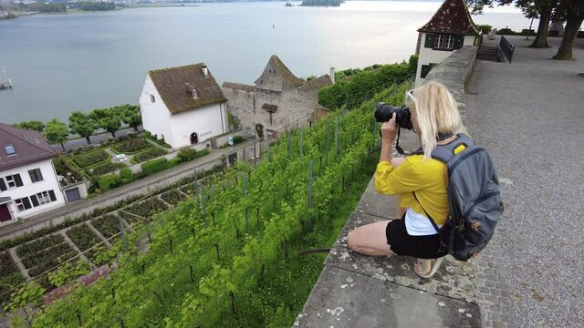 Woman photographer on top of Rapperswil-Jona village city by Zurich Lake in Switzerland. Lookout of terraced vineyards with an aerial view of Rapperswil-Jona cityscape in Swiss canton of St. Gallen.