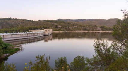 Beniarres's dam at dusk, with some reflections on the water, with a clear sky.