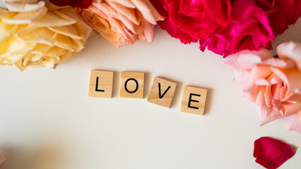 LOVE - napis z drewnianych kostek, róże w tle, różowy kolor - obrazy, fototapety, plakaty