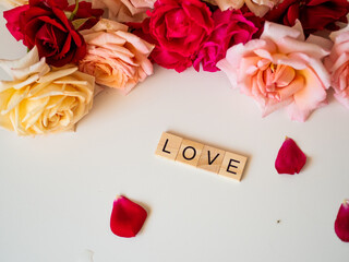 Fototapeta LOVE - napis z drewnianych kostek, róże w tle, różowy kolor obraz