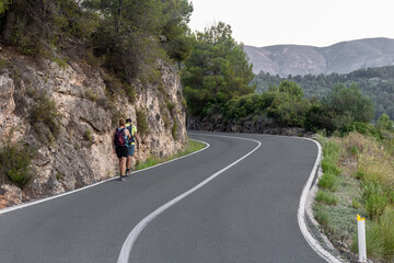 Obraz premium Couple of hikers walking along a road at dusk.