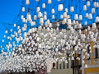 Fototapeta premium a lot of white lamps hang over the street. Illumination and decoration of the street.