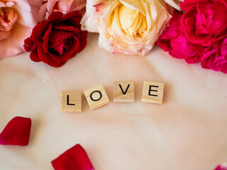 LOVE - napis z drewnianych kostek, róże w tle, różowy kolor © Klaudia Baran