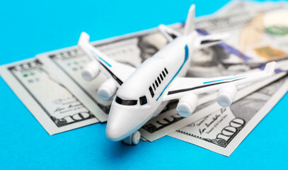 Airplane toy with dollar bills on blue.