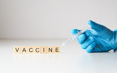 szczepionka - napis z drewnianych klocków, rękawiczka i strzykawka 