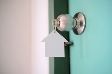 Home key with house keyring in keyhole on wooden door
