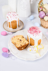 Easter cake with raisins in sugar glaze. festive pastries with pink sprinkles, painted eggs, pussy willow and Easter decor on a white background. religious holiday 