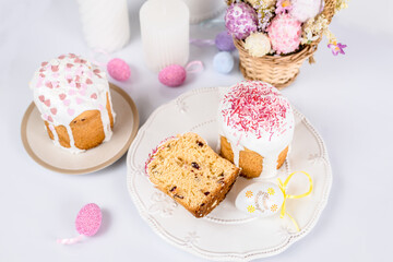 Easter cake with raisins in sugar glaze. festive pastries with pink sprinkles, painted eggs, pussy willow and Easter decor on a white background. religious holiday 